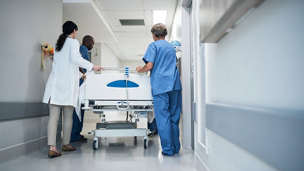 Rearview shot of a medical team pushing a patient down the hallway in a gurney.